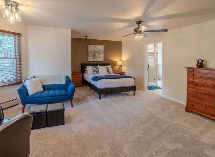This spacious bedroom offers a serene retreat with its plush carpeting and ample natural light.
