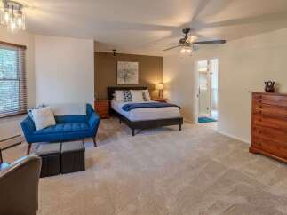 This spacious bedroom offers a serene retreat with its plush carpeting and ample natural light.