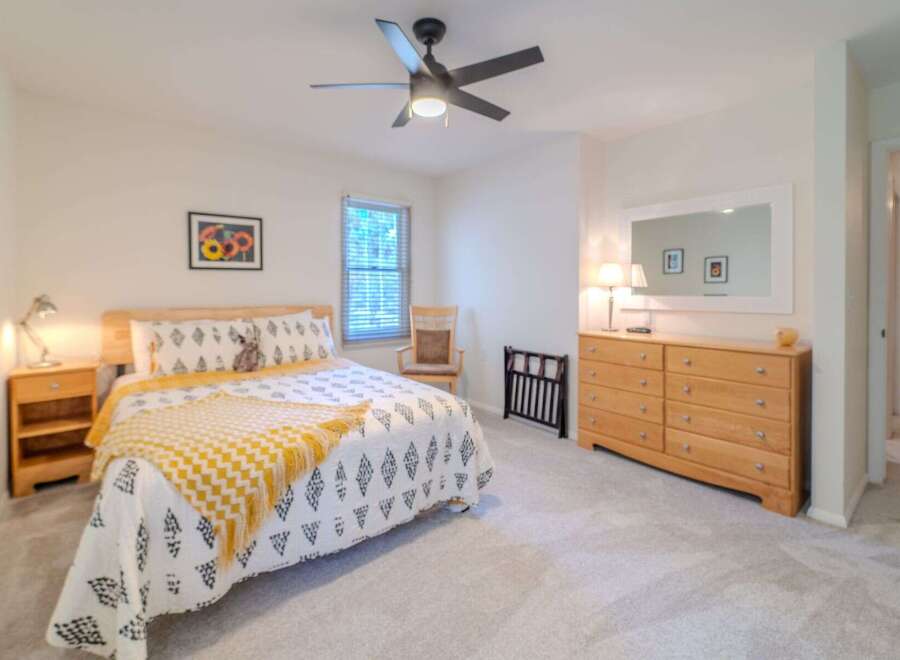 This inviting bedroom boasts a cozy atmosphere with its plush carpet and natural light.