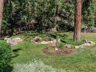 Discover a serene backyard oasis with lush green lawns and mature trees providing ample shade.