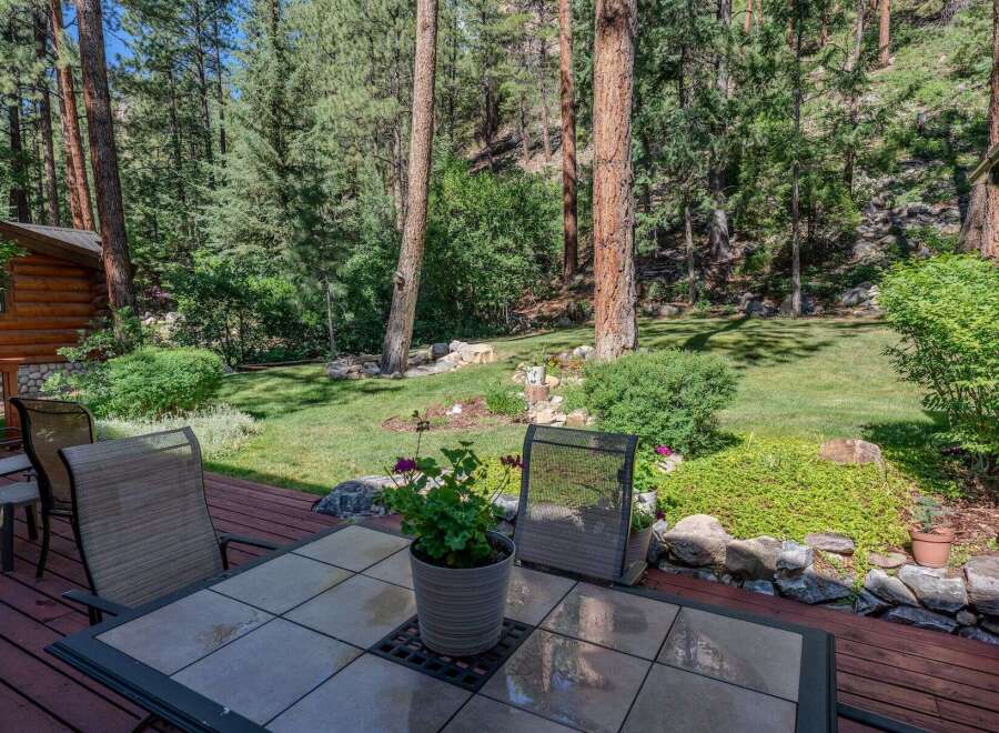Enjoy the serene mountain lifestyle from this charming log cabin's expansive deck, perfect for outdoor dining and relaxation.