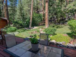 Enjoy the serene mountain lifestyle from this charming log cabin's expansive deck, perfect for outdoor dining and relaxation.