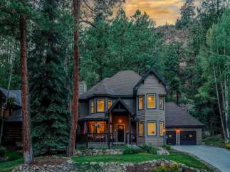 Nestled amidst towering pine trees and a scenic mountain backdrop, this stunning home offers a serene retreat.
