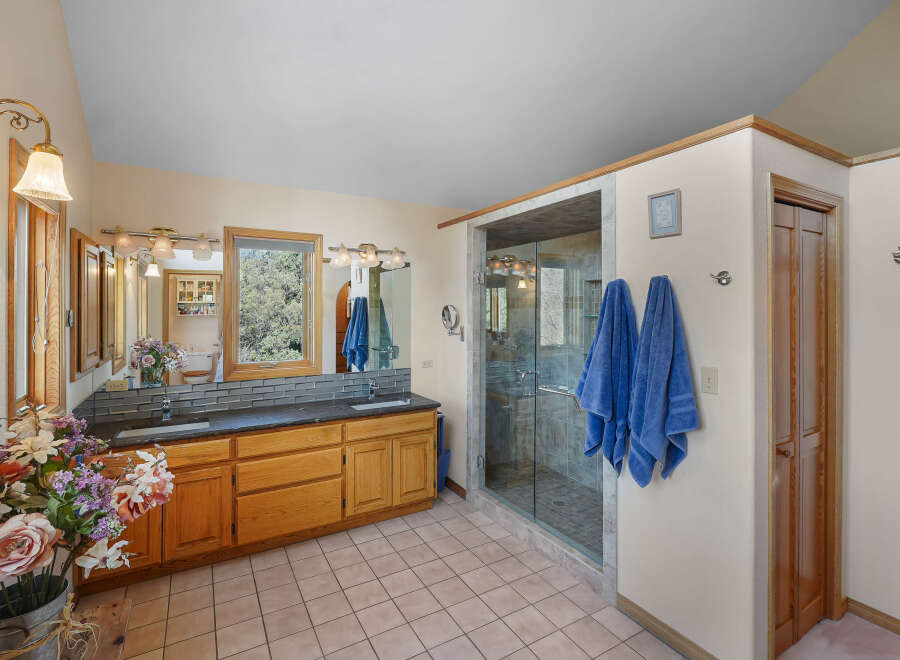 Step into a luxurious bathroom retreat! This space features a spacious walk-in shower, a double vanity with ample storage, and elegant lighting fixtures.
