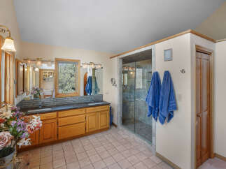 Step into a luxurious bathroom retreat! This space features a spacious walk-in shower, a double vanity with ample storage, and elegant lighting fixtures.
