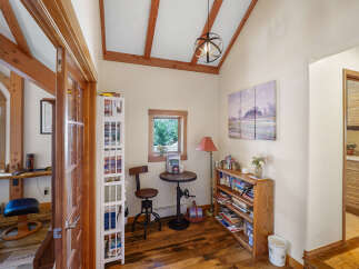 Step into this inviting home office, featuring a charming reading nook with a small round table and a unique adjustable stool.