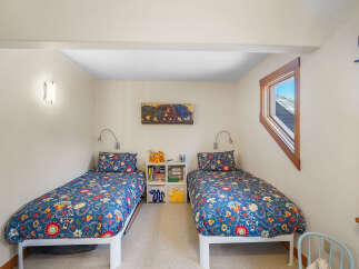 This charming bedroom features two twin beds with vibrant floral bedding, perfect for a shared space or guest room.