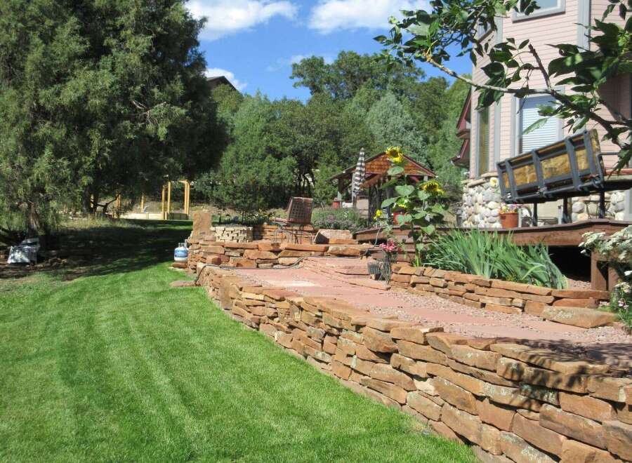 Discover the charm of this stunning property, featuring a beautifully landscaped yard and a meticulously crafted stone retaining wall.