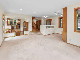 Step into this spacious living area featuring a plush carpet and an open-concept layout that seamlessly connects to the dining area and kitchen.