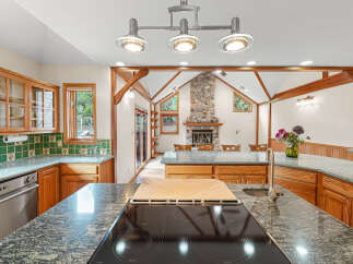 Experience the warmth of this inviting kitchen, featuring a stunning stone fireplace as its centerpiece.