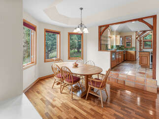 Enjoy meals in this charming dining area, featuring a beautiful wooden table and chairs bathed in natural light from large windows.