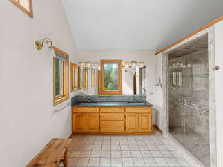 This spacious bathroom features a double vanity with ample storage and a large walk-in shower with elegant tilework.