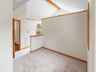 Discover this charming room with a vaulted ceiling and exposed wooden beams, creating an airy and inviting atmosphere.