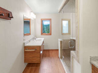 This modern bathroom features a sleek vanity with a granite countertop and a unique striped wood cabinet.