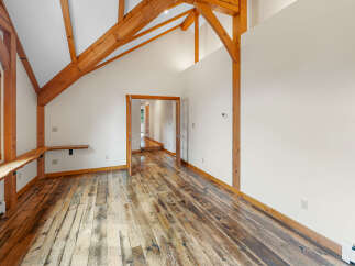 Experience rustic charm in this spacious room featuring exposed wooden beams and a vaulted ceiling.