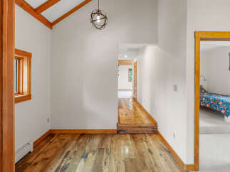Step into this charming home featuring a vaulted ceiling with exposed wooden beams and a unique globe pendant light.