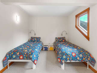 This charming bedroom features two twin beds, each adorned with vibrant floral bedding, creating a playful and inviting atmosphere.