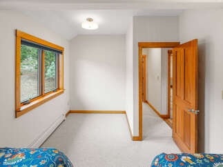 This charming bedroom features a large wooden-framed window offering picturesque views of the surrounding greenery.
