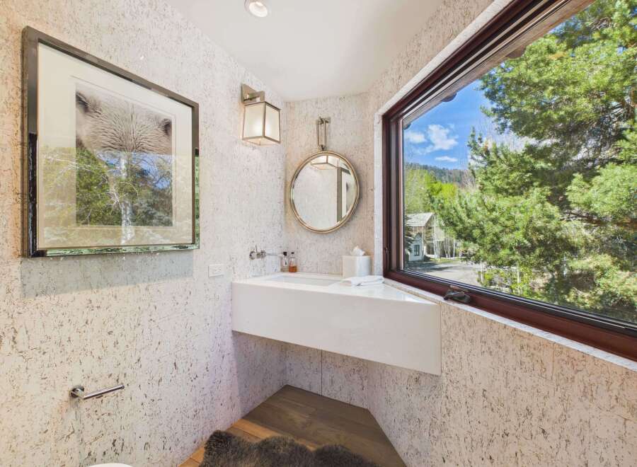 This stunning bathroom boasts a modern design with a sleek white sink and a large window offering breathtaking views of the surrounding nature.