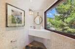 This stunning bathroom boasts a modern design with a sleek white sink and a large window offering breathtaking views of the surrounding nature.