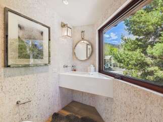 This stunning bathroom boasts a modern design with a sleek white sink and a large window offering breathtaking views of the surrounding nature.