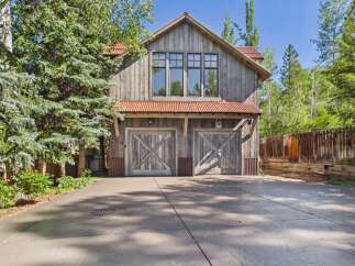 Discover this charming rustic-style garage featuring a weathered wood exterior and a corrugated metal roof.