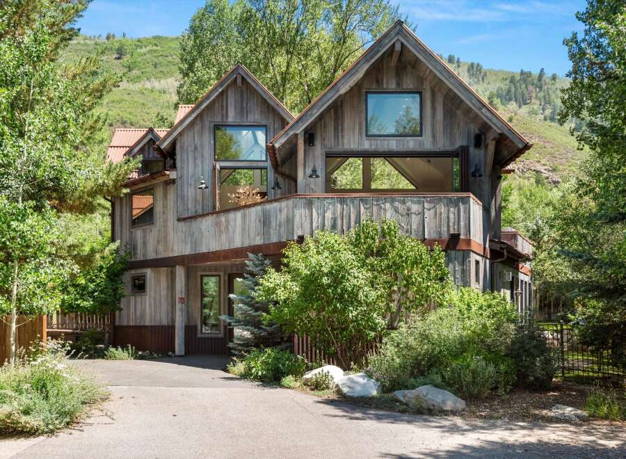 Experience rustic luxury in this stunning mountain home, featuring a unique architectural design with weathered wood siding and a copper roof.