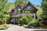 Experience rustic luxury in this stunning mountain home, featuring a unique architectural design with weathered wood siding and a copper roof.