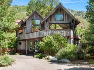 Experience rustic luxury in this stunning mountain home, featuring a unique architectural design with weathered wood siding and a copper roof.