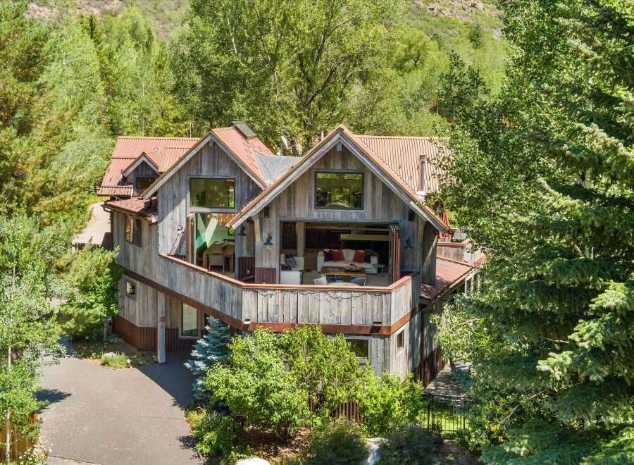 Nestled amidst lush greenery, this rustic mountain home offers a serene escape with its natural wood siding and corrugated metal roof.