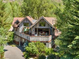 Nestled amidst lush greenery, this rustic mountain home offers a serene escape with its natural wood siding and corrugated metal roof.