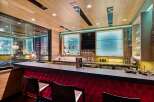 Experience ultimate entertainment in this custom home bar, featuring a sleek, modern design with a vibrant red tufted bar front and a spacious granite countertop.