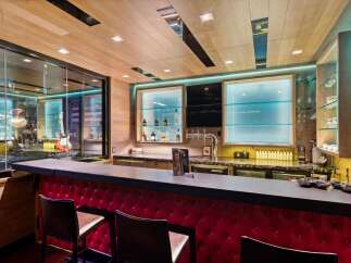 Experience ultimate entertainment in this custom home bar, featuring a sleek, modern design with a vibrant red tufted bar front and a spacious granite countertop.