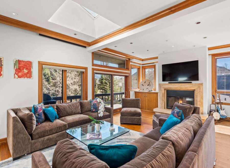 Experience luxury living in this stunning property, featuring a spacious living room with a cozy fireplace and a modern entertainment setup.