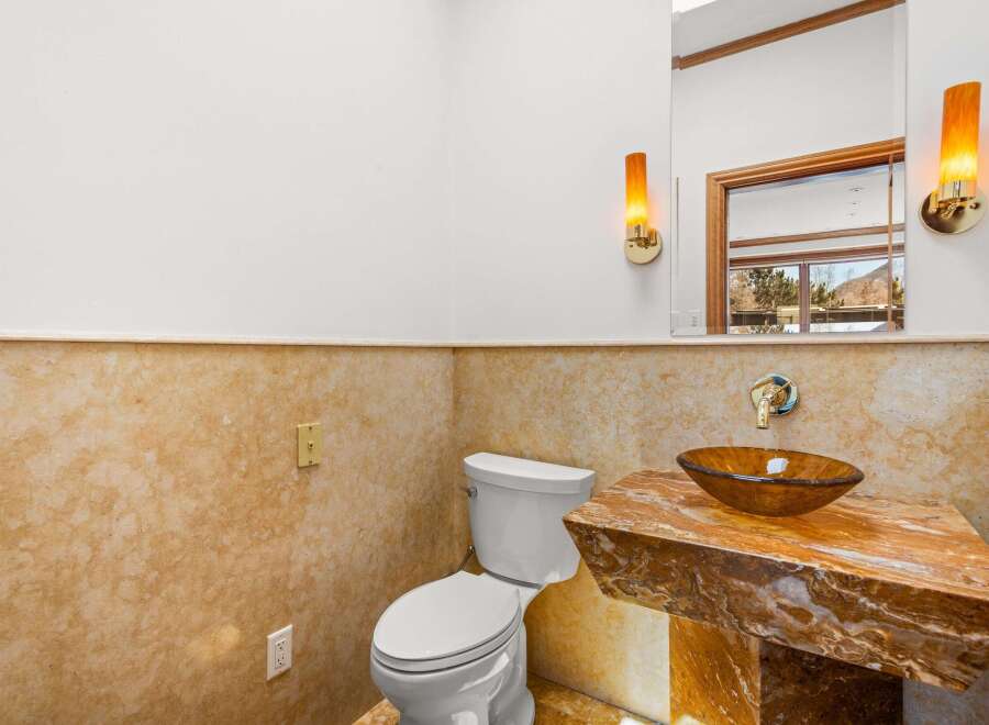 This stunning bathroom features a unique design with a marble countertop and a stylish vessel sink.