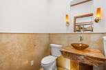 This stunning bathroom features a unique design with a marble countertop and a stylish vessel sink.