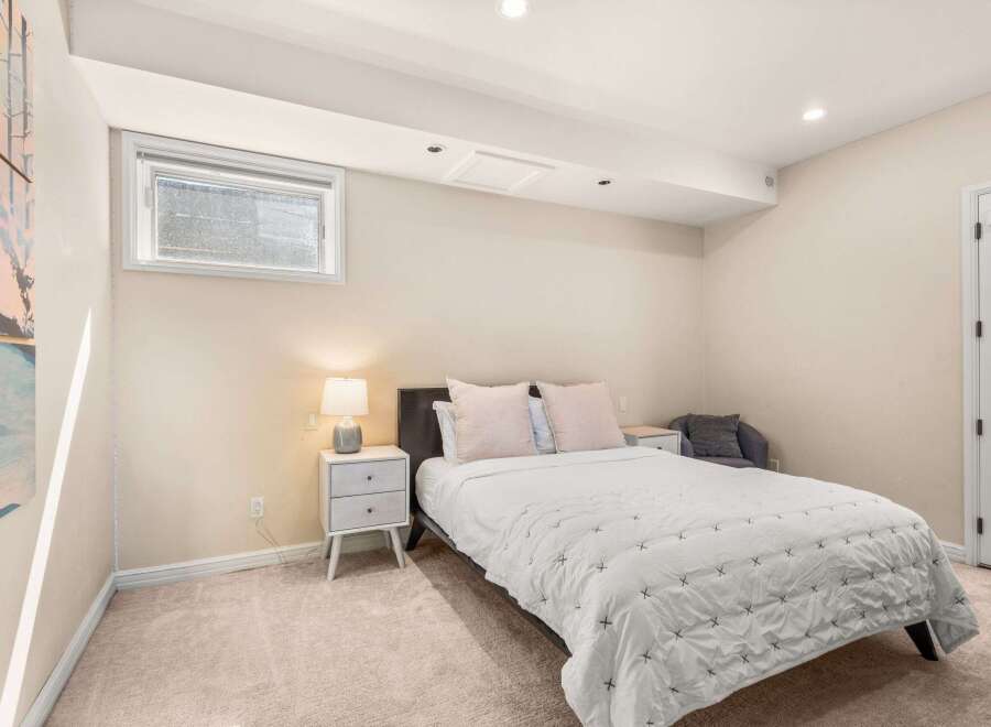 This cozy bedroom offers a serene retreat with its neutral color palette and ample natural light.