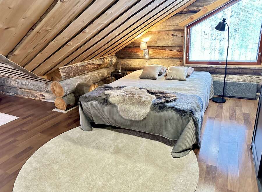This cozy cabin bedroom features a rustic wooden ceiling and walls, creating a warm and inviting atmosphere.