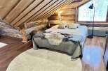 This cozy cabin bedroom features a rustic wooden ceiling and walls, creating a warm and inviting atmosphere.