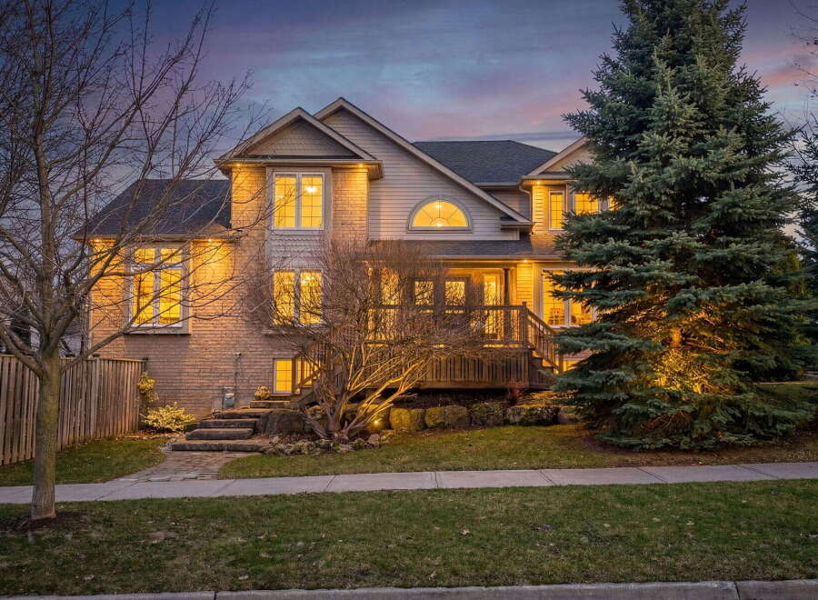 This stunning property boasts a beautiful exterior with a well-manicured lawn and mature trees.