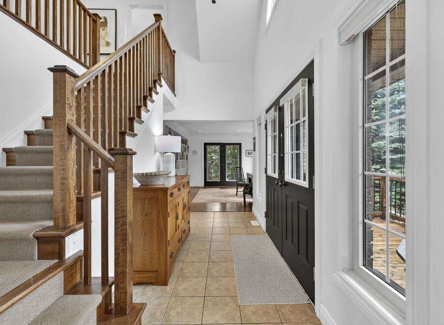 Step into luxury with this stunning entryway featuring a grand staircase and elegant hardwood details.