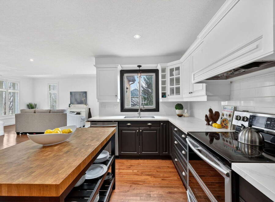 This stunning kitchen boasts a modern design with sleek white cabinetry and contrasting dark lower cabinets, creating a sophisticated aesthetic.