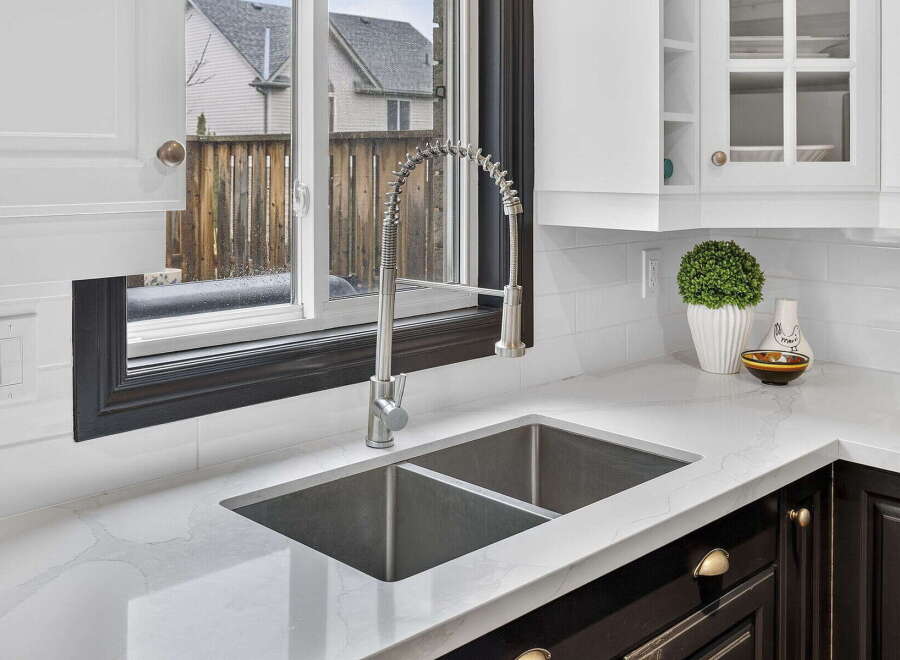 This stunning kitchen boasts a modern design with sleek countertops and a stainless steel sink.
