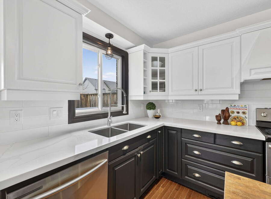 This stunning kitchen boasts a modern design with sleek white cabinetry and contrasting dark lower cabinets, creating a stylish and functional space.