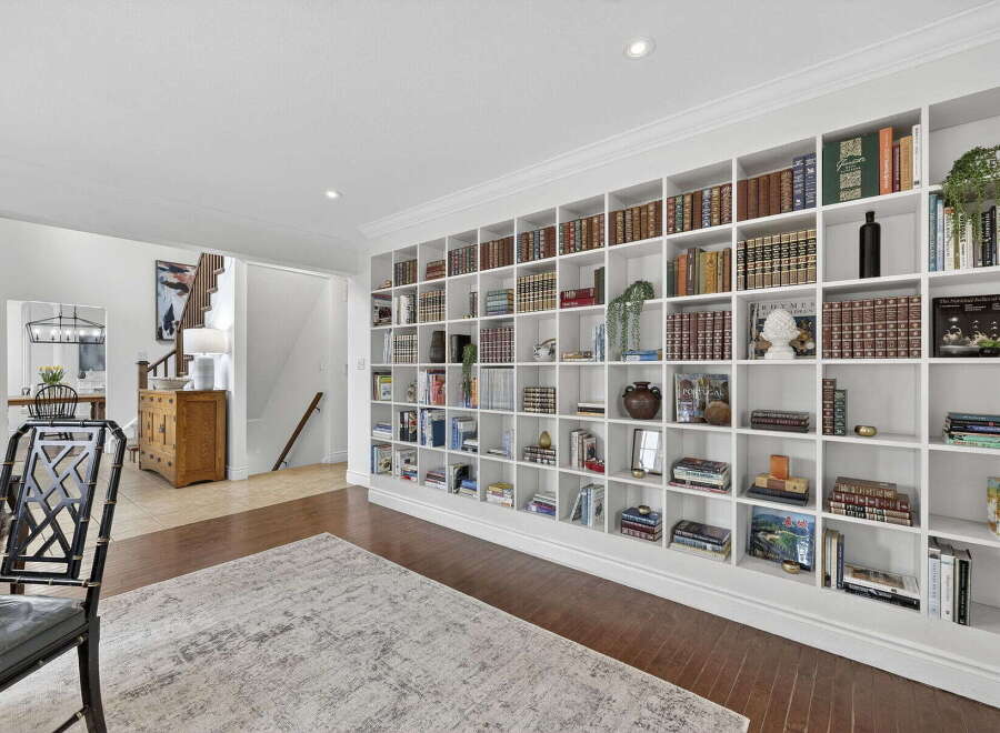 This stunning property boasts a custom-built bookshelf that spans an entire wall, perfect for showcasing your literary collection and adding a touch of elegance to the living space.