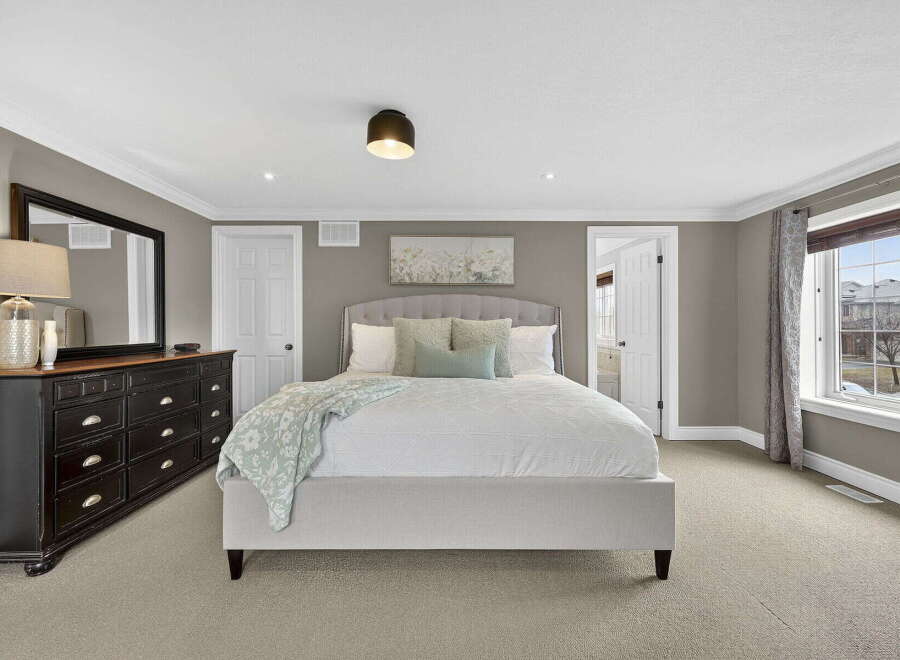 This spacious bedroom offers a serene retreat with its neutral color palette and ample natural light.