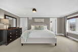 This spacious bedroom offers a serene retreat with its neutral color palette and ample natural light.