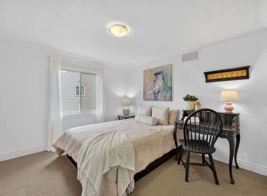 Step into this charming bedroom, featuring a cozy bed and a stylish desk.