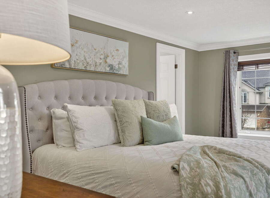 This inviting bedroom showcases a serene ambiance with its plush, tufted headboard and soft, neutral color palette.