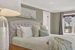 This inviting bedroom showcases a serene ambiance with its plush, tufted headboard and soft, neutral color palette.